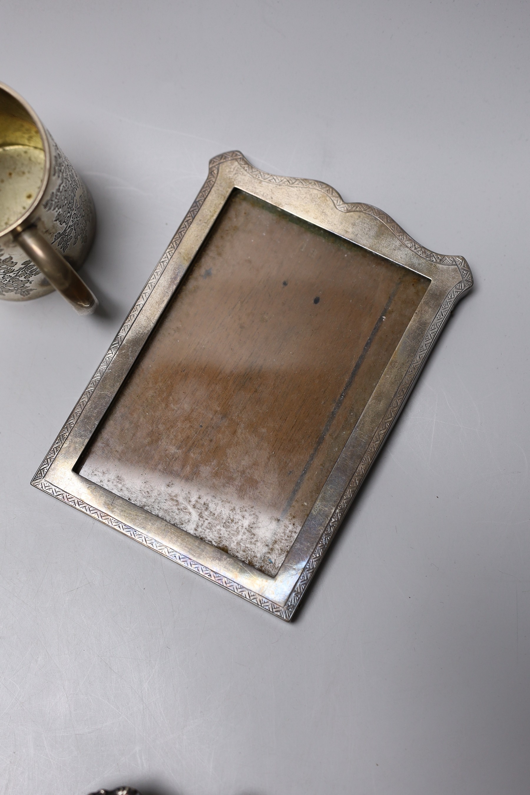 A Victorian engraved silver christening mug, London, 1890, 81mm, a silver napkin ring, a repousse silver dish and three silver mounted photograph frames.